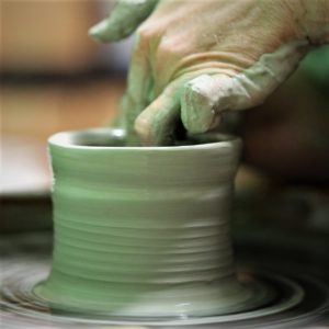 Amanda wheel throwing a cylinder from a grey clay body.